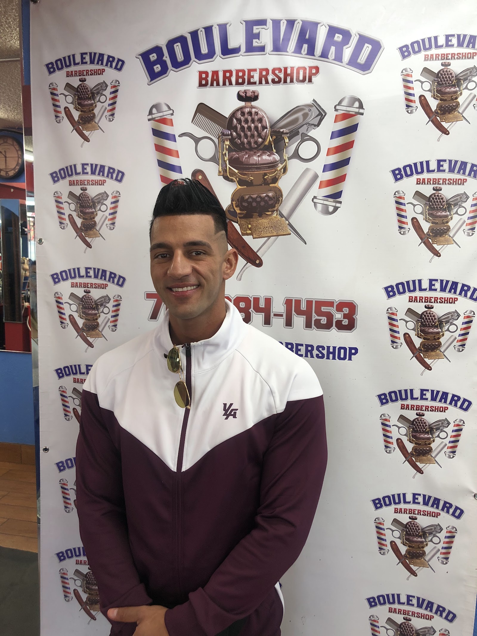 Man with fresh fade haircut in front of Boulevard Barbershop banner